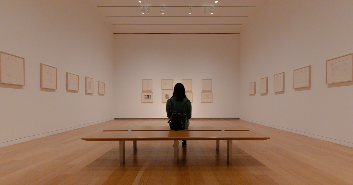 a woman sitting on a bench in an art gallery
