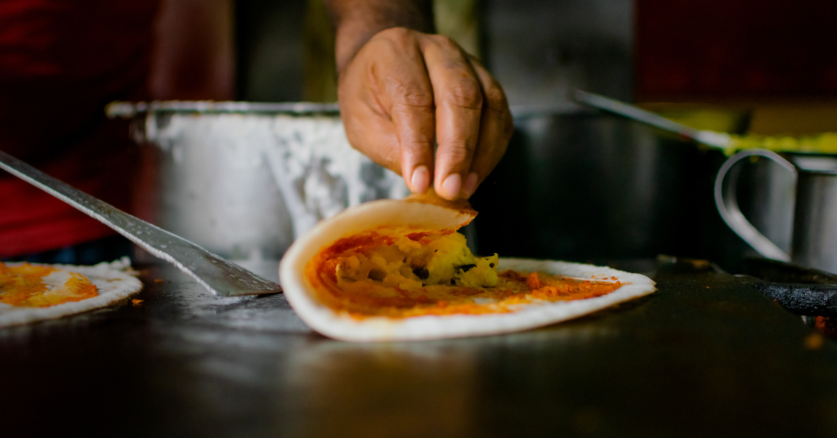 A dosa being folded on the pan